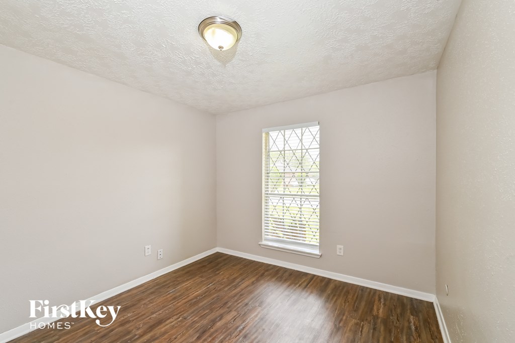 the living room of an empty house with wood flooring and a window