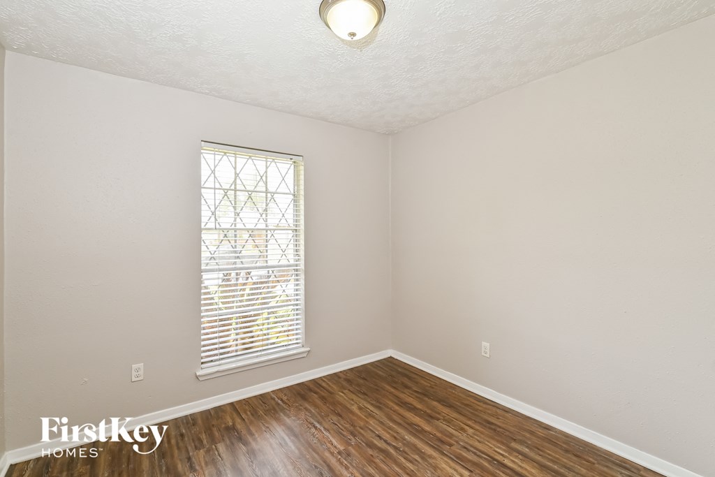 the living room of a small house with wood flooring and a window