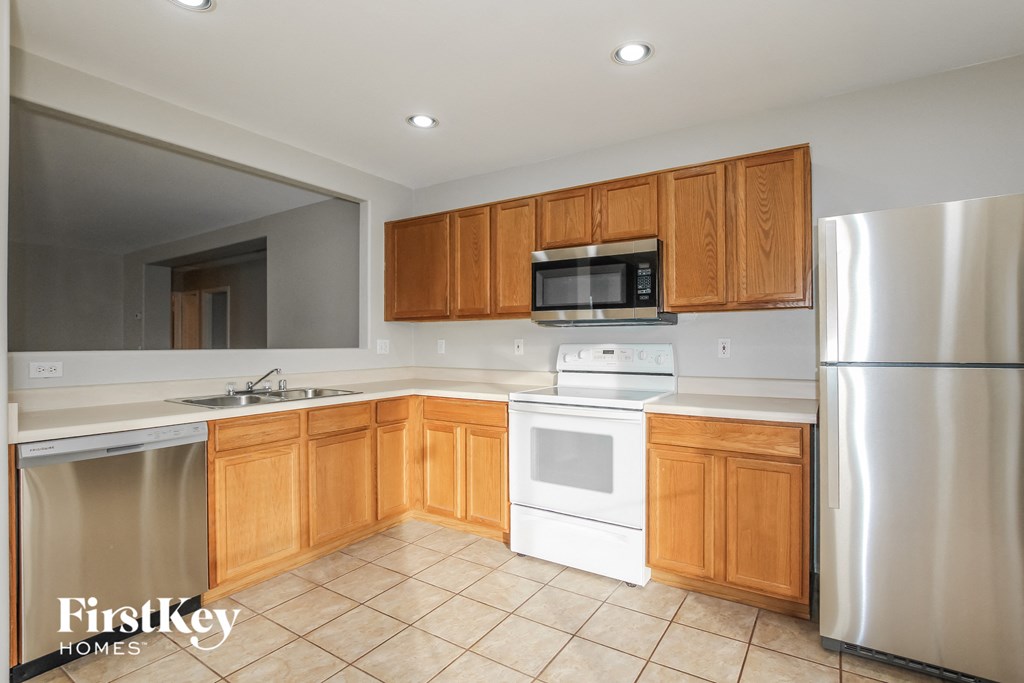 an empty kitchen with white appliances and wooden cabinets
