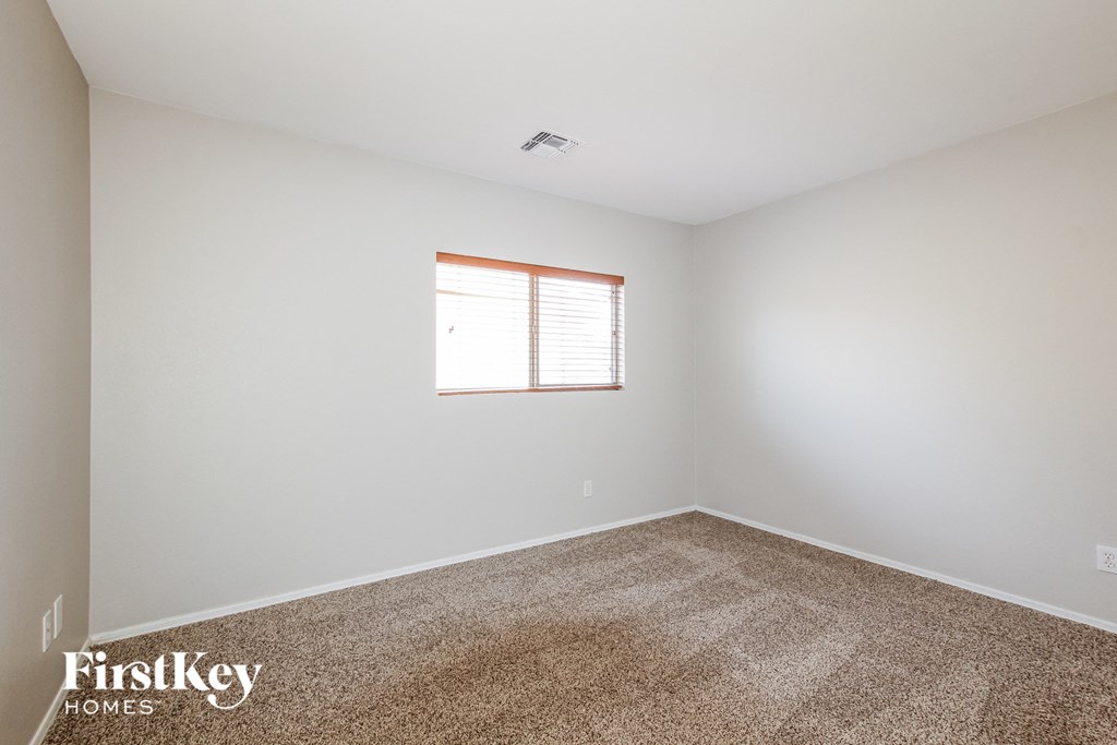 a bedroom with white walls and carpet and a window