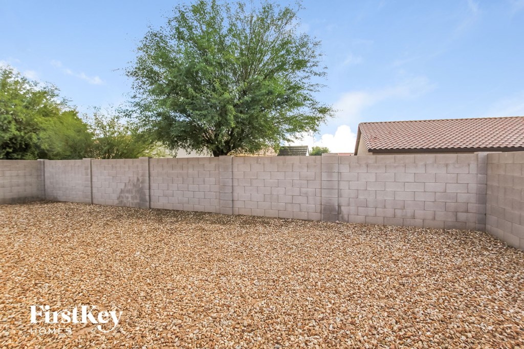 a retaining wall in a backyard with gravel and a tree