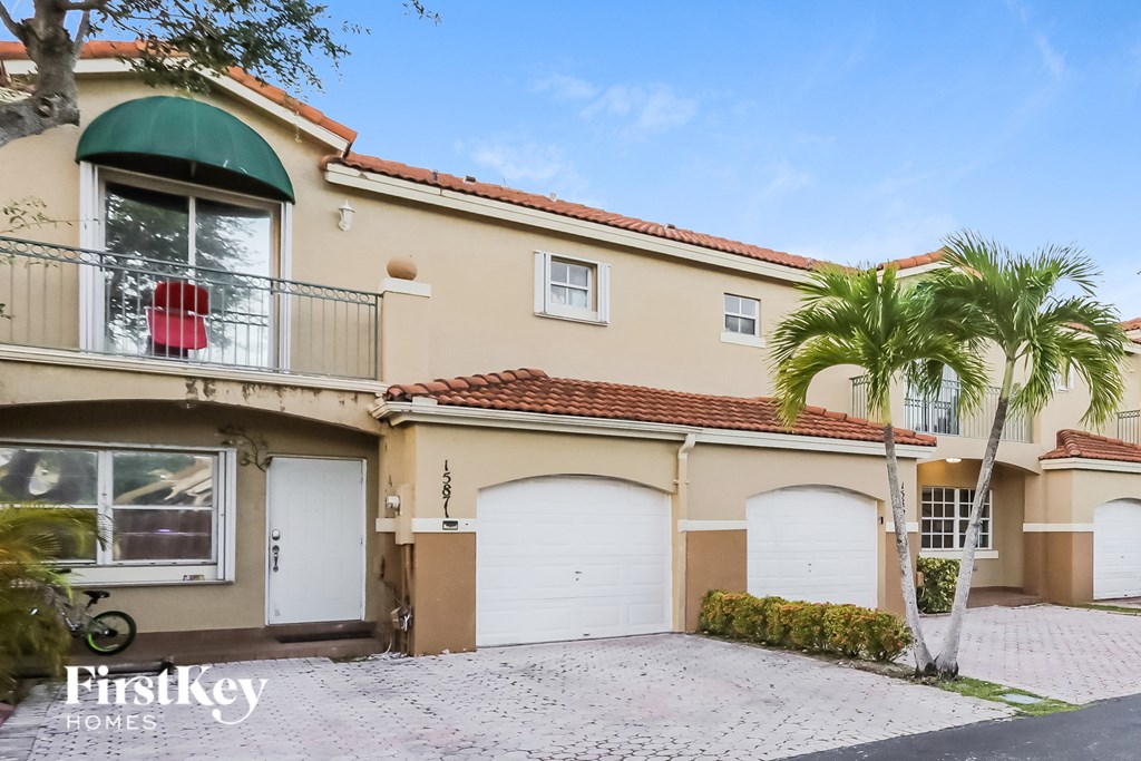 a house with two garages and two palm trees