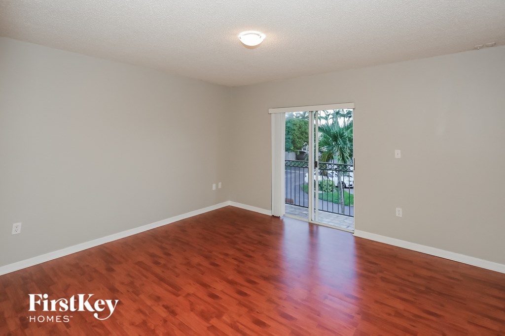 a living room with wood floors and a door to a balcony