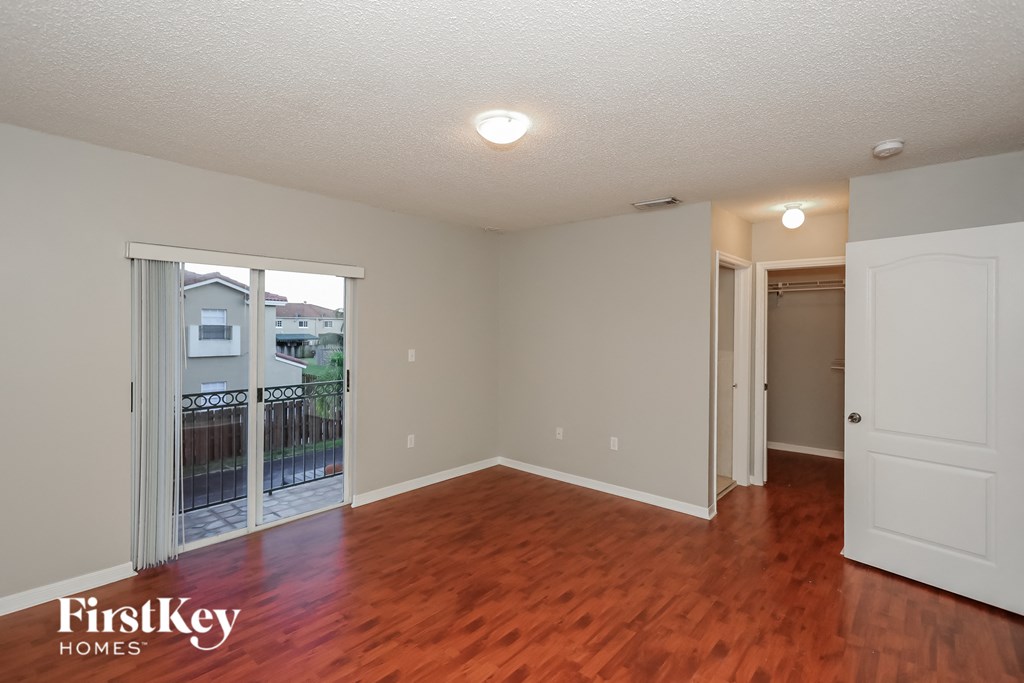 a living room with a wood floor and a door to a balcony