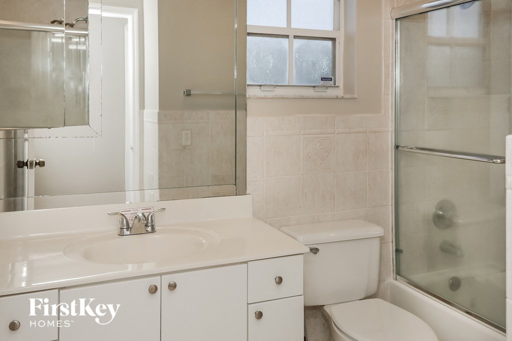 a white bathroom with a shower toilet and sink