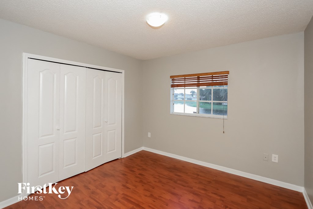 a bedroom with wood floors and white walls and a window