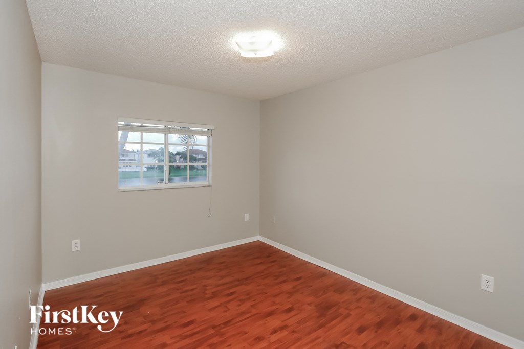 a bedroom with wood flooring and a window
