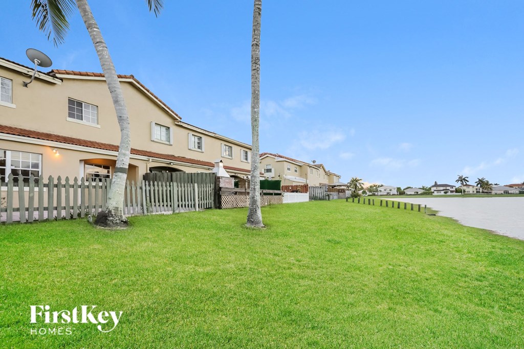a yard with palm trees and a white picket fence
