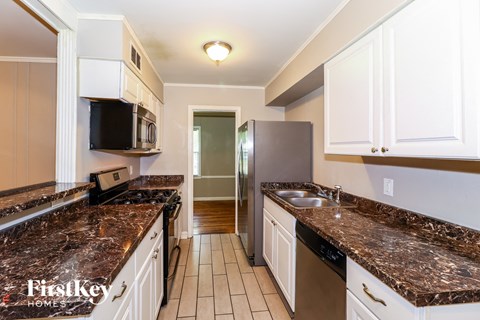 a kitchen with granite counter tops and white cabinets