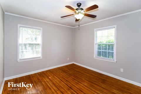 a bedroom with wood floors and a ceiling fan