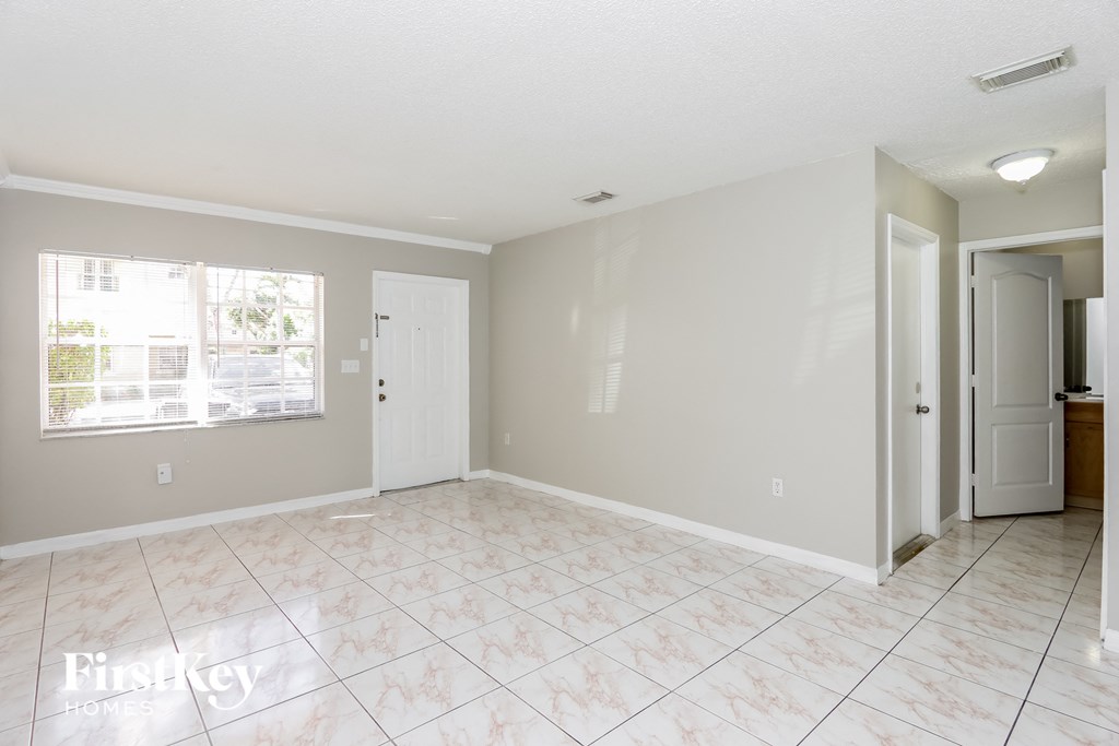 an empty living room with a white tiled floor and a window