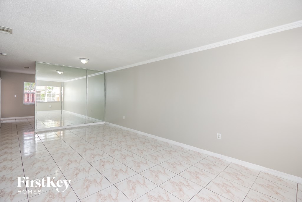 an empty living room with a mirrored closet and a tiled floor