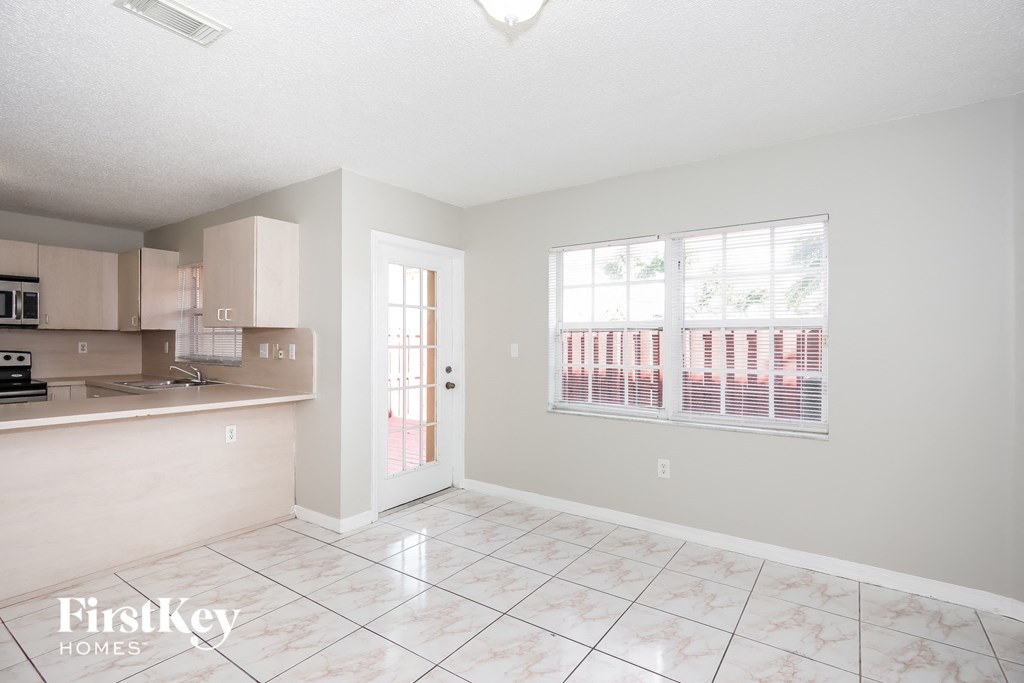 an empty living room with a kitchen and a large window