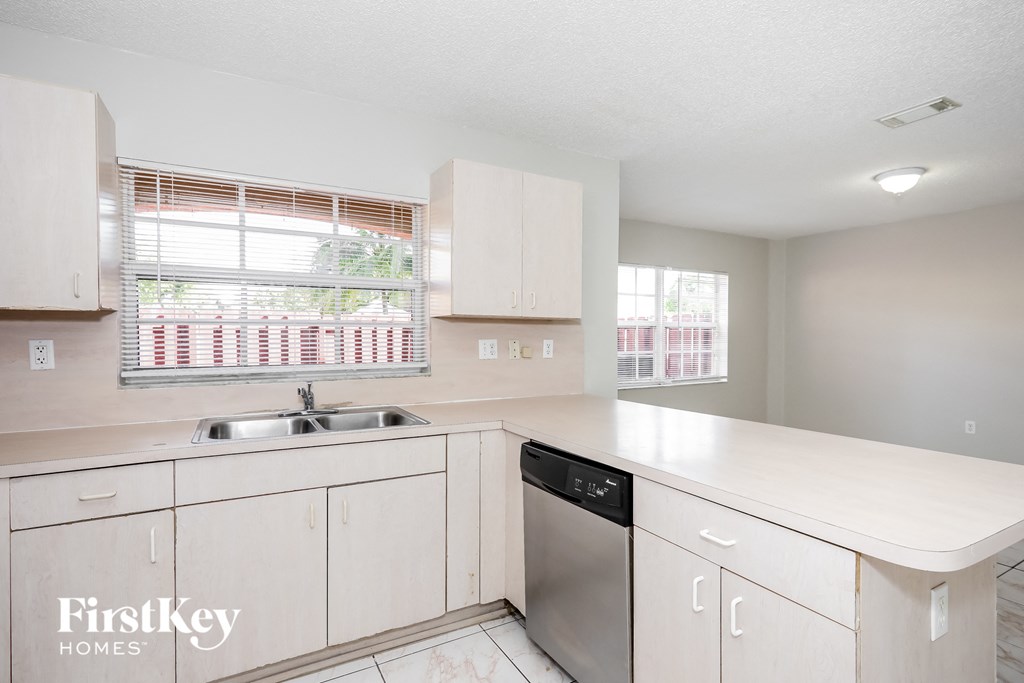 a kitchen with white cabinets and a sink and a window