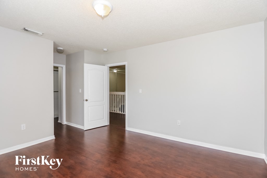 an empty living room with wood floors and white walls