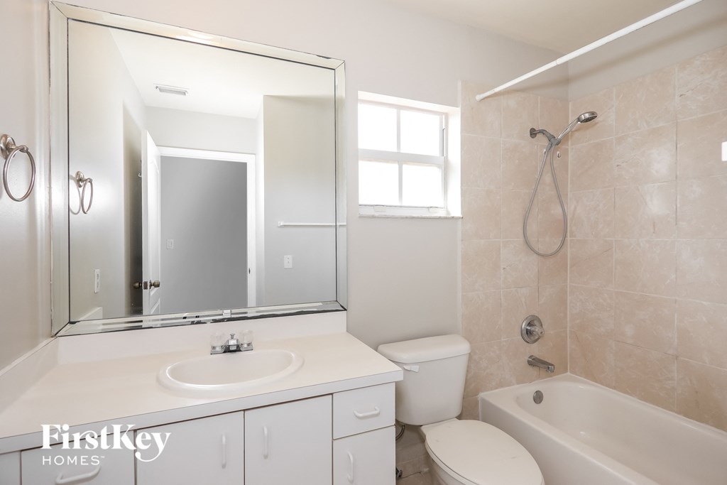 a white bathroom with a tub sink and toilet and a mirror