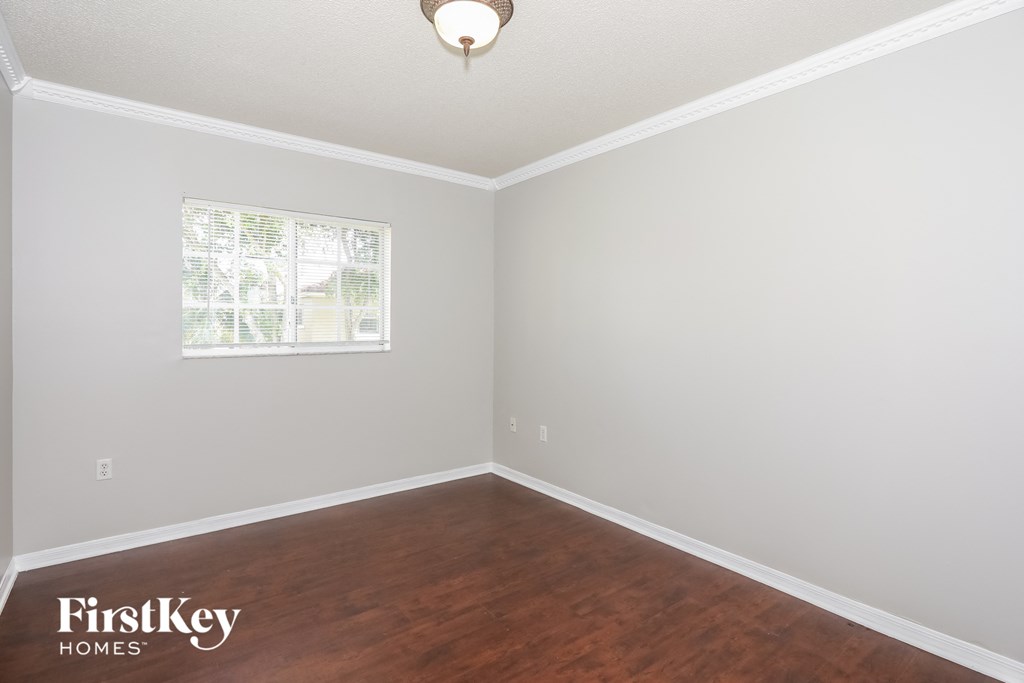 a bedroom with wood flooring and a window