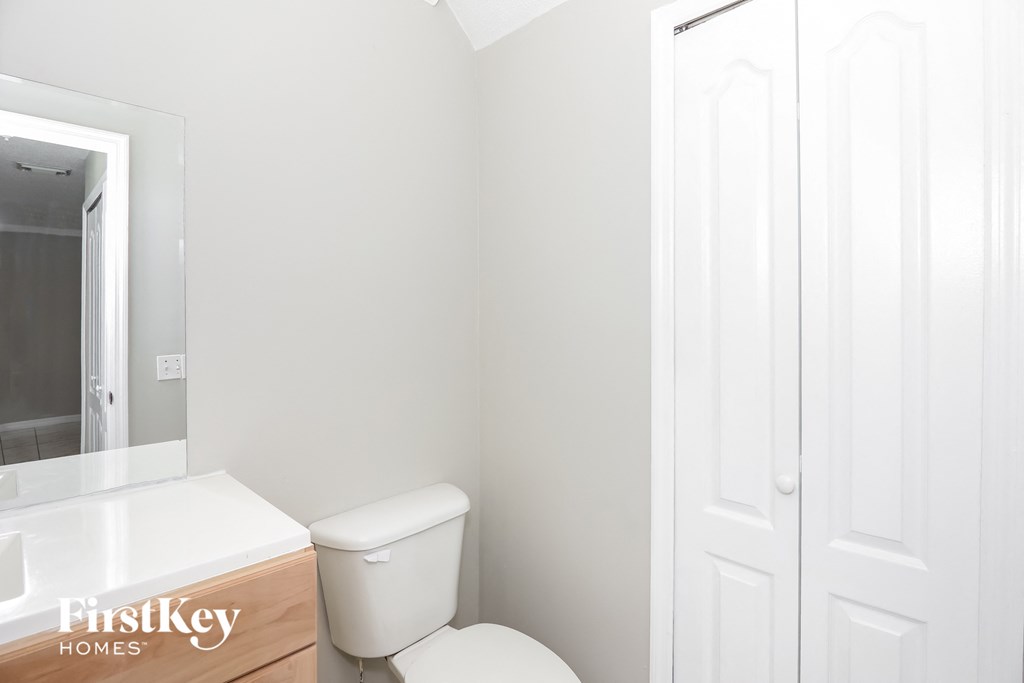 a white bathroom with a toilet and a mirror