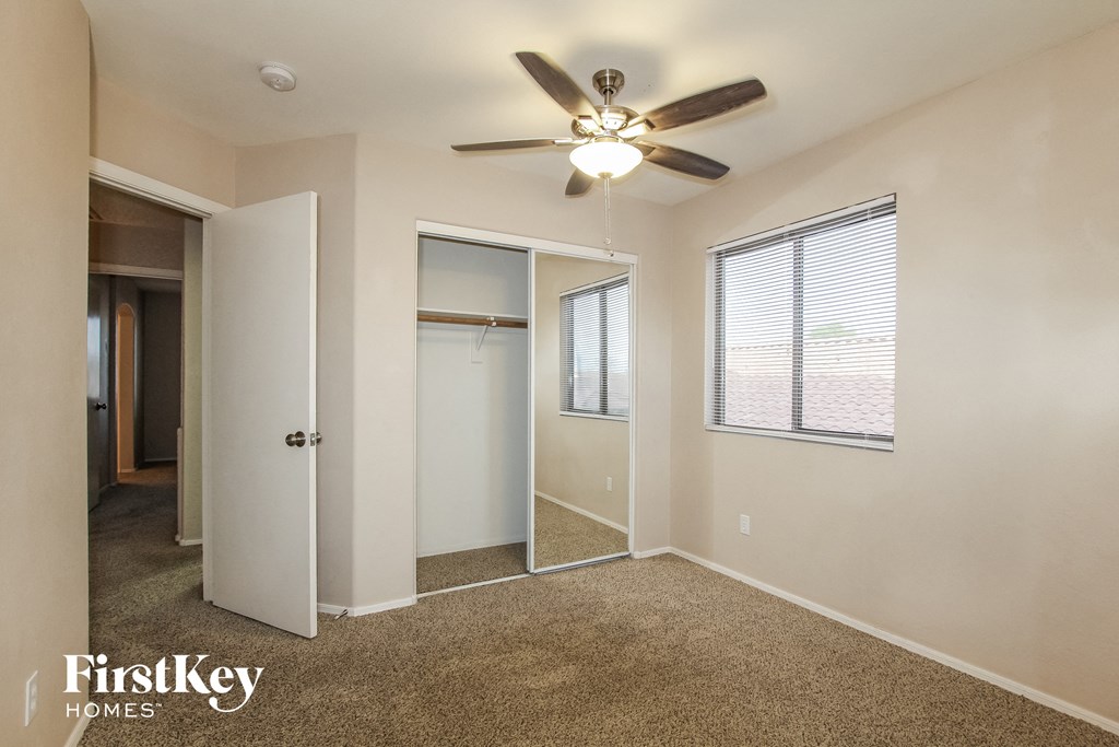 a bedroom with a ceiling fan and a door to a closet