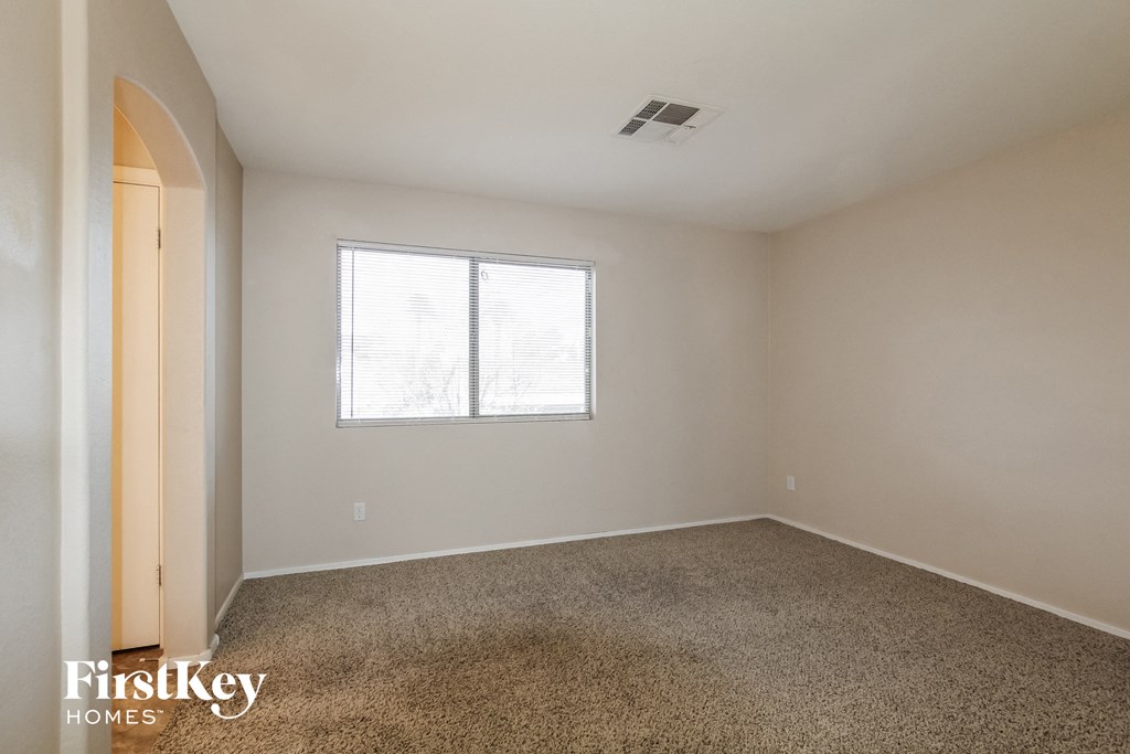 the living room of an apartment with carpet and a window