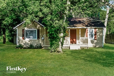 a small house with a porch and a tree