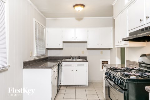 A kitchen with white cabinets and a black stove top.