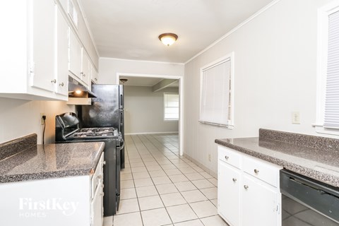 A kitchen with a granite counter top and white cabinets.