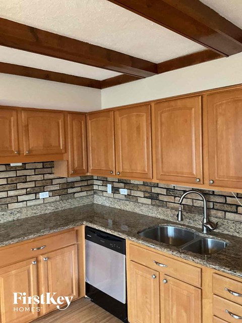 A kitchen with wooden cabinets and a stone backsplash.