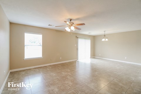 an empty living room with a ceiling fan and tiled floor