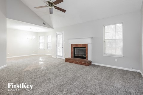 A spacious living room with a fireplace and a ceiling fan.
