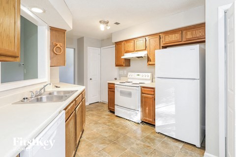 A kitchen with white appliances and wooden cabinets.