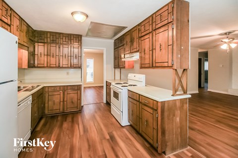 a kitchen with wooden cabinets and white appliances and a wood floor