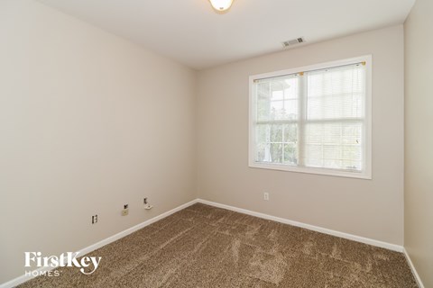 a spacious room with carpet and a window