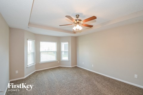 an empty living room with a ceiling fan and windows