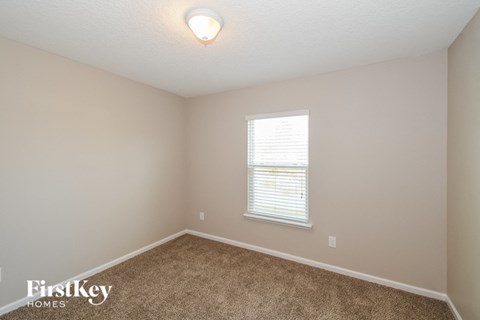 a bedroom with beige carpet and a window