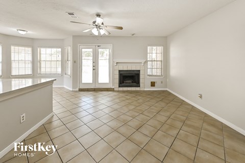 an empty living room with a fireplace and a ceiling fan