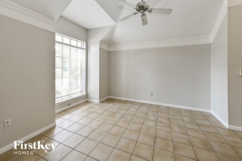 an empty living room with a ceiling fan and a window