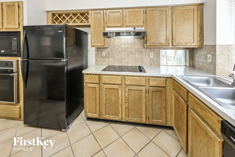 a kitchen with wooden cabinets and a black refrigerator