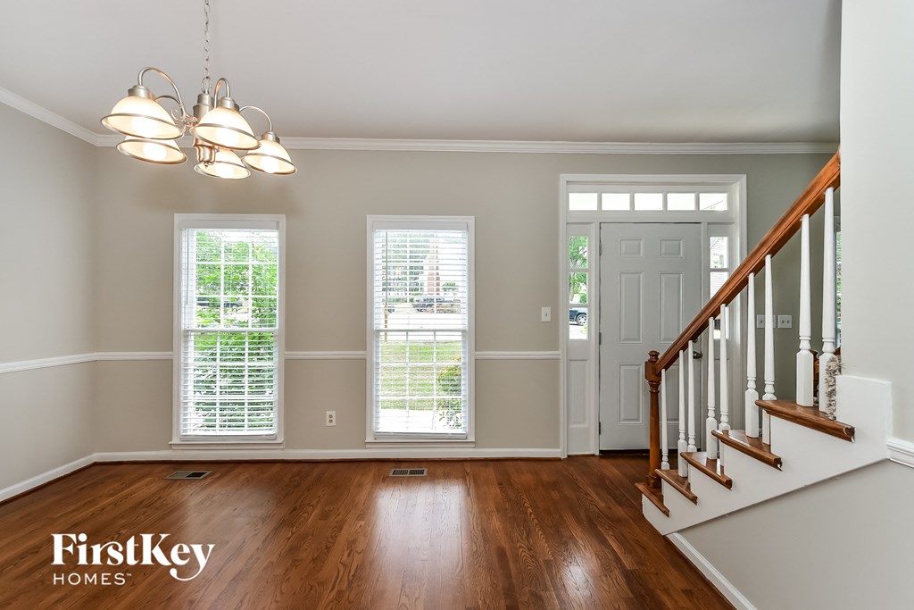 an empty living room with a staircase and a white door