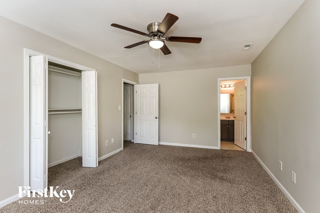 a master bedroom with carpet and a ceiling fan