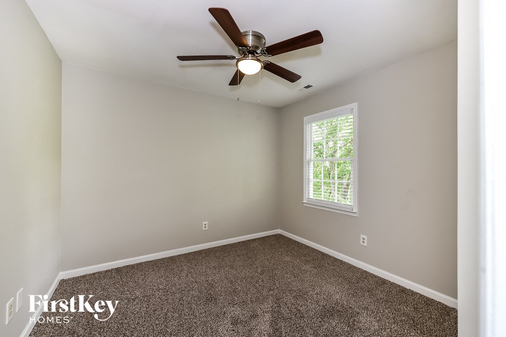 an empty room with a ceiling fan and a window