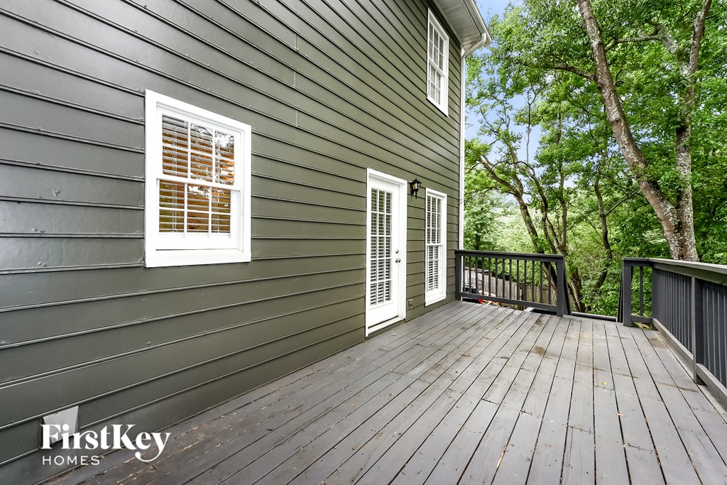 the deck on the side of a house with trees