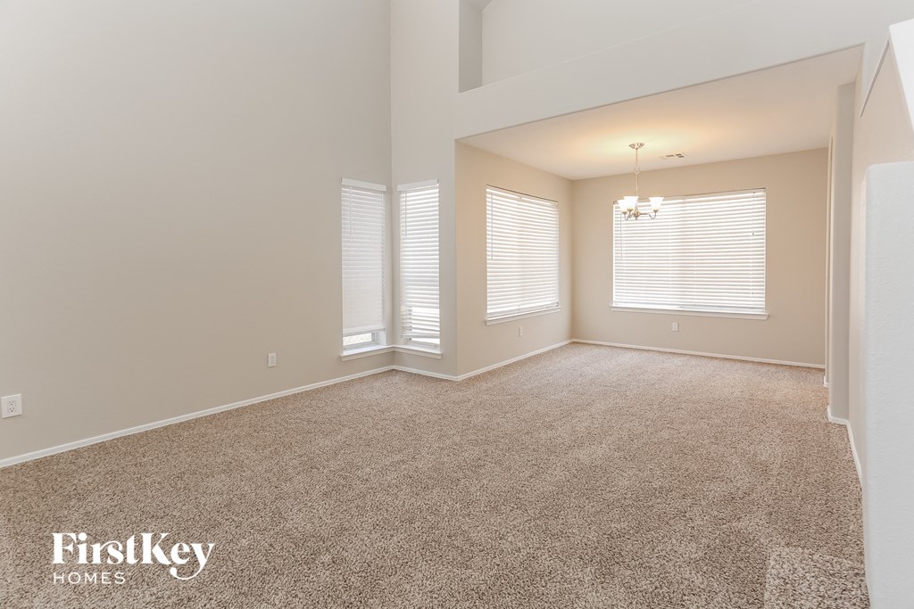a spacious living room with a carpeted floor and windows