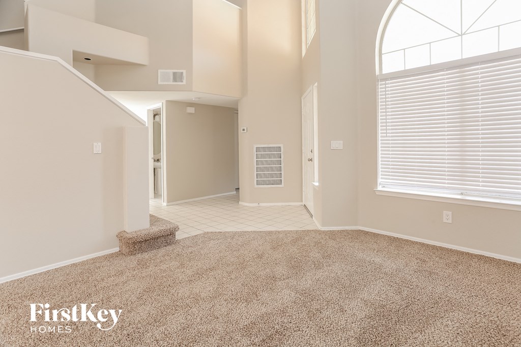an empty living room with a carpeted floor and a large window