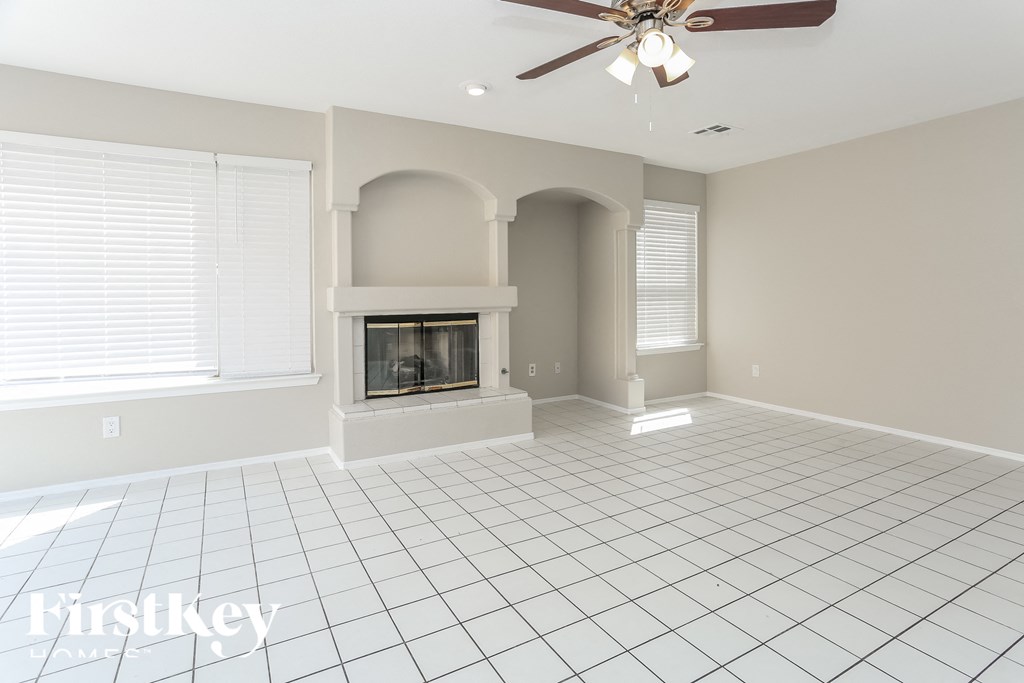 an empty living room with a fireplace and a ceiling fan