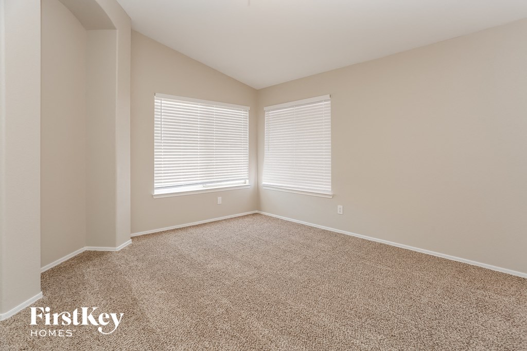an empty living room with two windows and a carpet