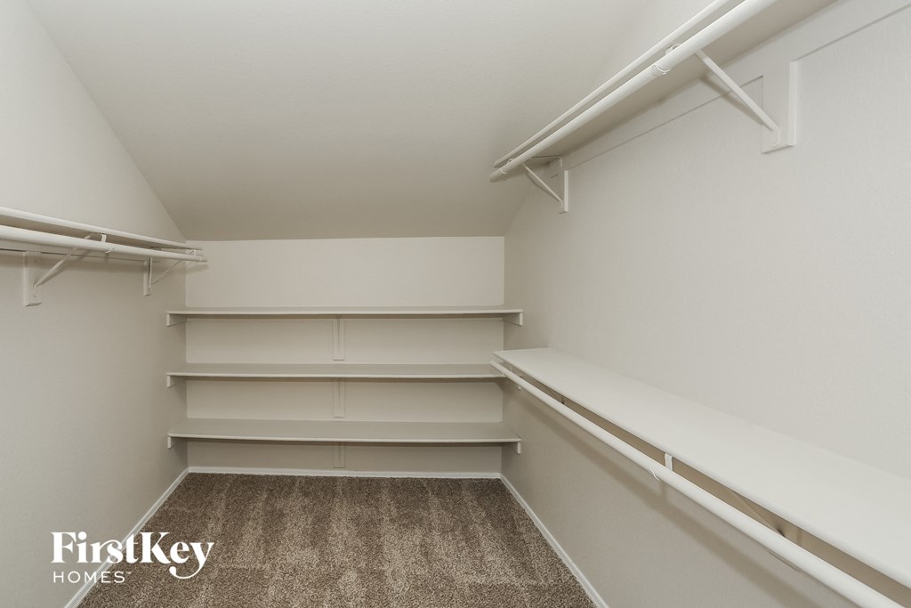a walk in closet with white shelves and white walls and carpet