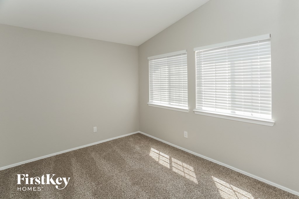 a bedroom with a carpeted floor and two windows