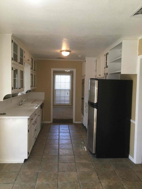 A kitchen with a black refrigerator and white cabinets.