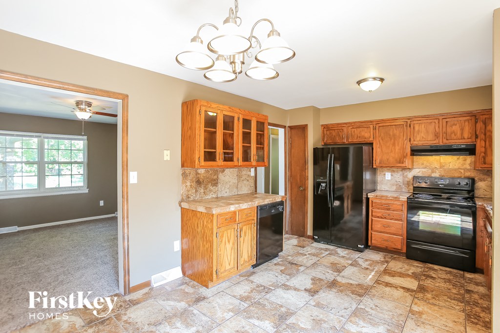 a kitchen with wooden cabinets and a black refrigerator
